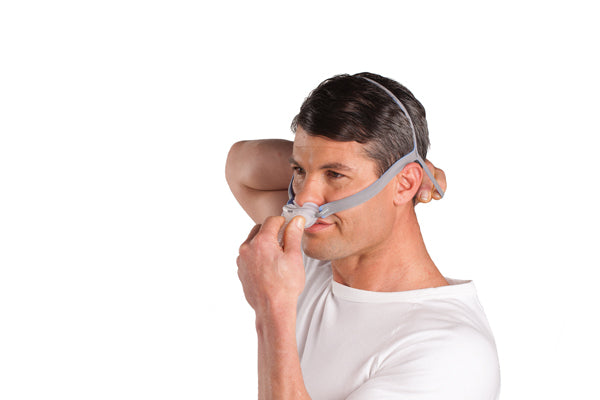 Man putting on the ResMed AirFit P10 Nasal Pillow CPAP Mask