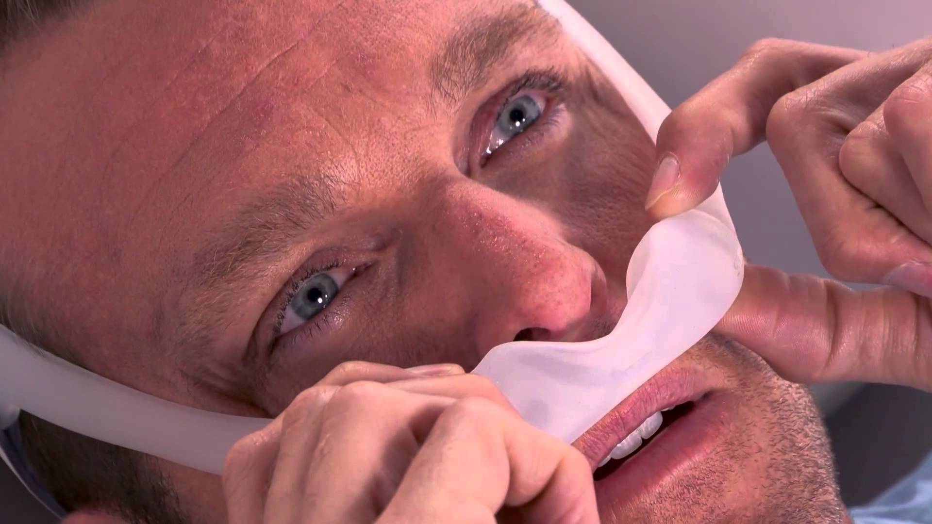 Man putting on Philips Respironics DreamWear under the nose mask